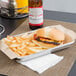 A tray of food with a burger and fries on a Choice Natural Kraft basket liner.