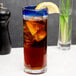 A Libbey Aruba Zombie glass with a cobalt blue rim filled with iced tea and a lemon wedge.