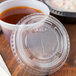 A Solo Ultra Clear PET plastic lid with a straw slot on a plastic container with a brown liquid.