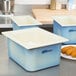 A kitchen counter with blue Carlisle Coldmaster containers and a white square bowl.