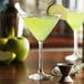 A Libbey martini glass filled with green liquid and a slice of apple on the rim.