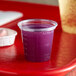 A Solo translucent plastic medicine cup with purple liquid on a red tray.
