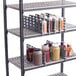 A shelf with Cambro shelf dividers holding bottles and condiments.