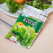 A Classic Gourmet fat free ranch dressing portion packet on a plate of salad.