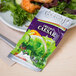 A Classic Gourmet Creamy Caesar Dressing portion packet on a plate of salad.