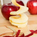 Spiral apple slices and peel with a Matfer Bourgeat apple peeler on a table.