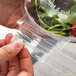 A hand holding a Polar Pak clear plastic bowl with a salad inside.