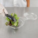 A gloved hand holds a Polar Pak clear plastic bowl with a lid over a bowl of lettuce.