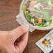 A hand holding a Polar Pak clear plastic container with a salad inside.
