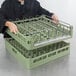 A woman holding a Vollrath light green open end steam table pan rack.
