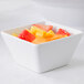 An American Metalcraft white square melamine bowl filled with fruit.