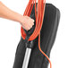 A hand holding the orange cable for a Hoover Task Vac commercial vacuum cleaner.