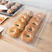 A table with a Cambro display tray of bagels and muffins on a counter in a bakery.