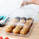 A person using a Cambro clear polycarbonate tray to bag a muffin at a bakery.