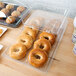 A clear plastic tray with a hinged cover holding a variety of bagels and muffins.
