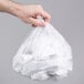 A hand holding a white Lavex high density plastic trash bag.