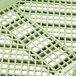 A close up of a green plastic flatware rack grid.