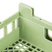 A close up of a light green plastic flatware rack with holes.
