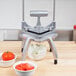 A Nemco Easy Chopper II vegetable dicer on a counter with bowls of sliced tomatoes and chopped onions.