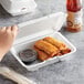 A white Dart foam takeout container with fried egg rolls inside and a perforated hinged lid.