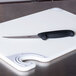 A Victorinox curved boning knife with a black handle on a cutting board.