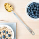 A spoon in a bowl of cereal and blueberries with the American Metalcraft Hammered Stainless Steel Portioned Server.