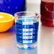 A Libbey professional measuring glass filled with blue liquid and an orange slice.