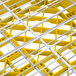 A yellow and silver metal grid with white dividers holding plates.