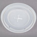 A close-up of a white plastic lid with a straw slot and a cross on it.