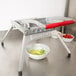 A Vollrath Redco Lettuce King vegetable slicer on a metal surface with a bowl of chopped vegetables.