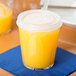 A Dinex clear plastic tumbler with a straw and orange juice.
