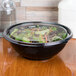 A Sabert FreshPack clear flat lid on a round bowl of salad.