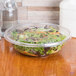 A salad in a clear plastic bowl with a clear flat lid.