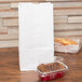 A Duro white paper bag with a loaf of bread and a container of coffee next to it.