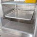 A stainless steel Avantco bun pan rail with trays inside of a refrigerator.
