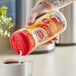 A person pouring Nestle Coffee-Mate Hazelnut Non-Dairy Coffee Creamer into a cup of coffee.