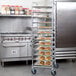 A large stainless steel Regency sheet pan rack with trays of croissants on it.