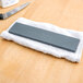 A Victorinox Crystolon sharpening stone on a towel next to a knife.