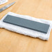 A knife on a white towel with a grey rectangular sharpening stone.