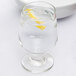 A Libbey footed all purpose goblet filled with water and a lemon slice on a table.