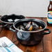 A black Hendi enameled steel mussel pot with mussels in it on a table.