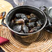 A black Hendi enameled steel pot filled with mussels on a table.