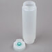 A white plastic bottle with a green cap and a blue round object inside.