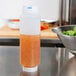 A FIFO Innovations squeeze bottle of salad dressing on a counter next to a bowl of salad.
