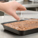 A hand holding a Solut plastic container over a brownie.