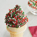 A chocolate ice cream cone with Christmas sprinkles.