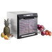 A Excalibur stainless steel food dehydrator with fruits, vegetables, and pineapple on the trays.