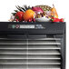 A close-up of a pear and other fruits and vegetables in a Excalibur 10-tray stainless steel food dehydrator.
