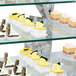 A display of cakes on a glass shelf using Eastern Tabletop stainless steel "L" shaped corners with two integrated levels.