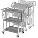 A gray Carlisle folding utility cart with three shelves and wheels.